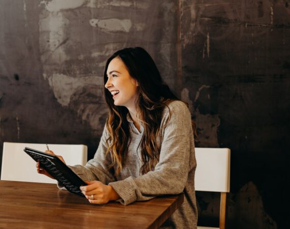 woman sitting around table holding tablet