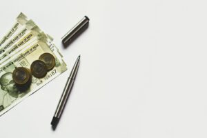 智慧理財,開創財富未來 32 gray pen beside coins on Indian rupee banknotes