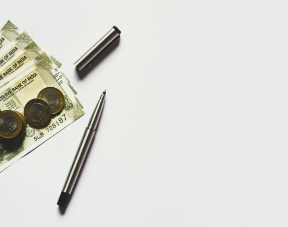 gray pen beside coins on Indian rupee banknotes